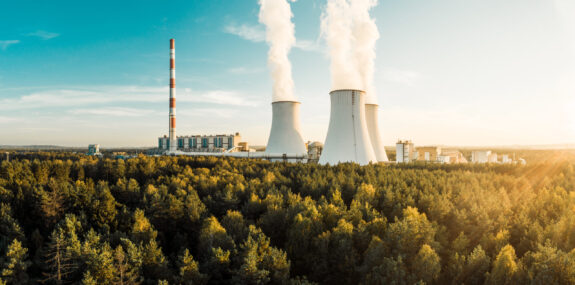 A Power plant with white smoke over it's chimneys