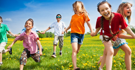 Large group of children running in the dandelion spring field