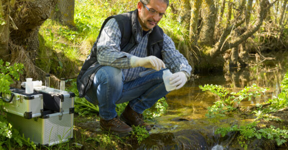 View of a Biologist take a sample in a river. Scientist and biologist hydro-biologist takes water samples for analysis.