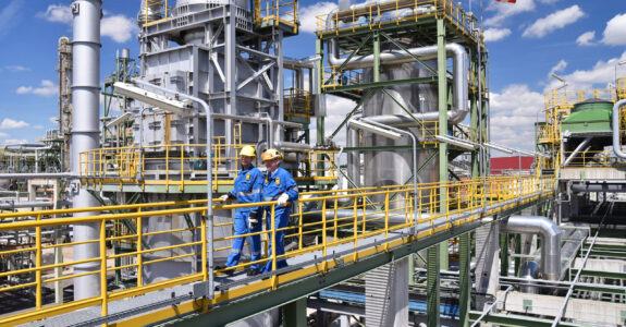 chemical industry plant - workers in work clothes in a refinery with pipes and machinery chemical industry plant - workers in work clothes in a refinery with pipes and machinery