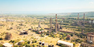 Aerial view derelict industrial zone with overgrown ruins smokestacks and contaminated wasteland in Rustavi Georgia.Summer landscape.Europe long-term environmental damage from pollution and neglect