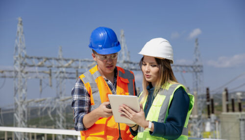 Young workers looking and checking wind turbines at field