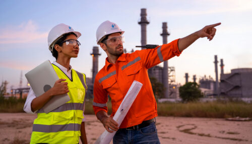 Two,Engineers,Working,With,Laptop,At,Front,Oil,And,Gas